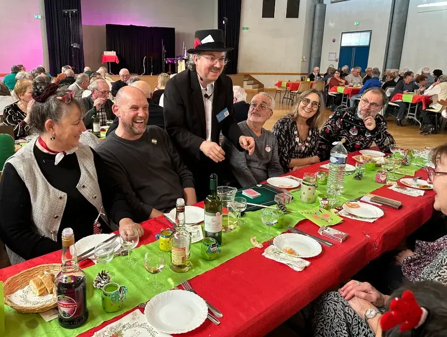 Sylvio, chapeau haut de forme, fait un tour à une longue table de convives dans une grande salle des fêtes