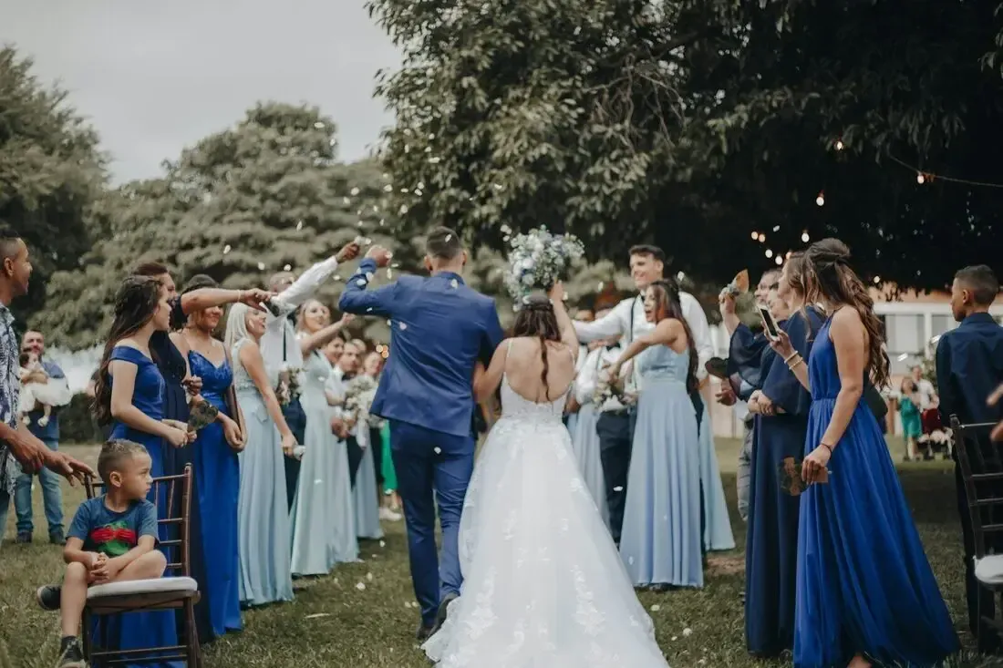 Cortège de mariage en plein air : la mariée en robe blanche s’avance entre deux haies d’invités en robes bleues